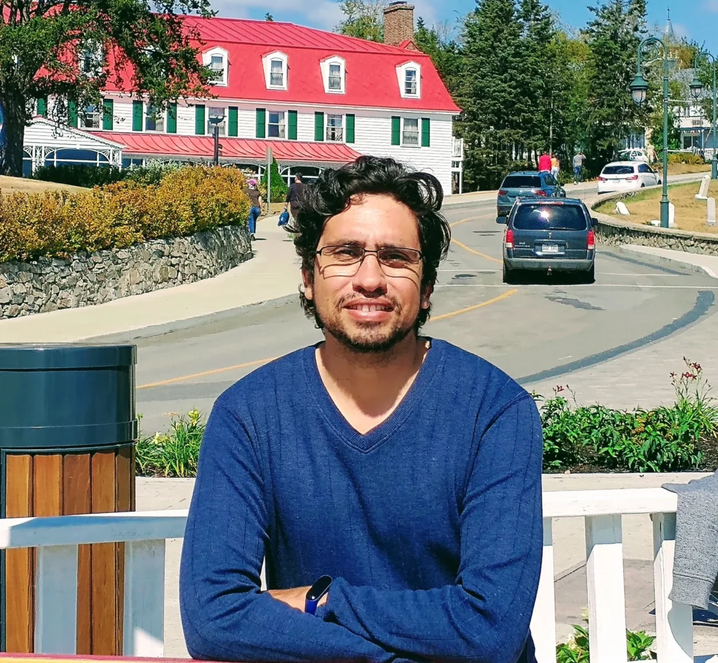 Jalves Nicacio, sitting on a bench in front of the Manoir Richelieu in La Malbaie, Québec